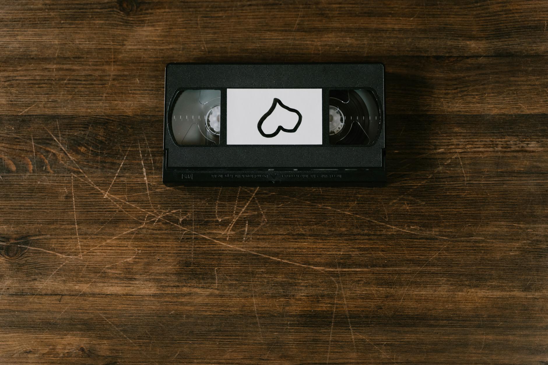A nostalgic VHS tape with a heart-shaped label on a rustic wooden surface.