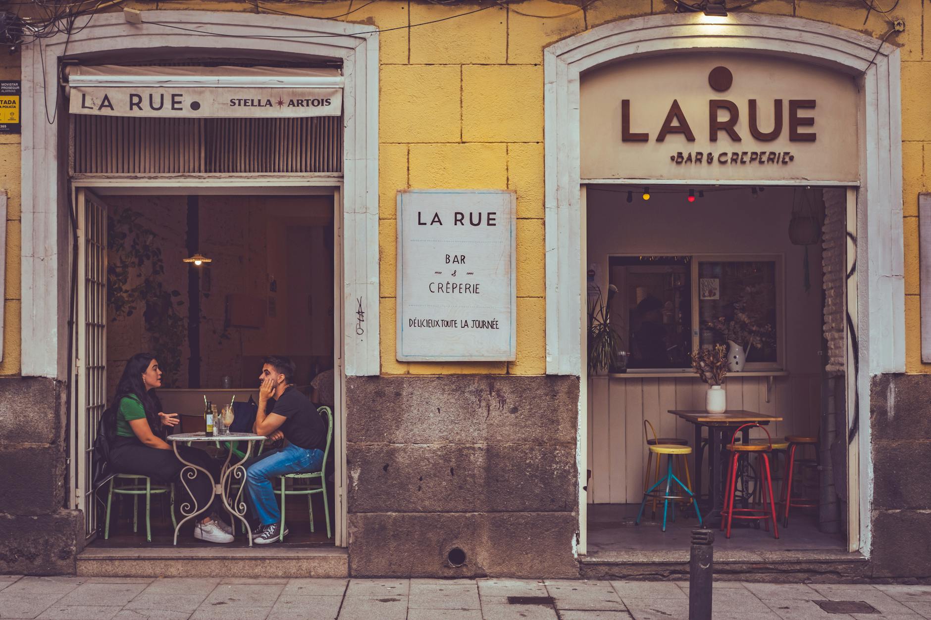 Casual outdoor café setting in Madrid featuring two people enjoying a drink.