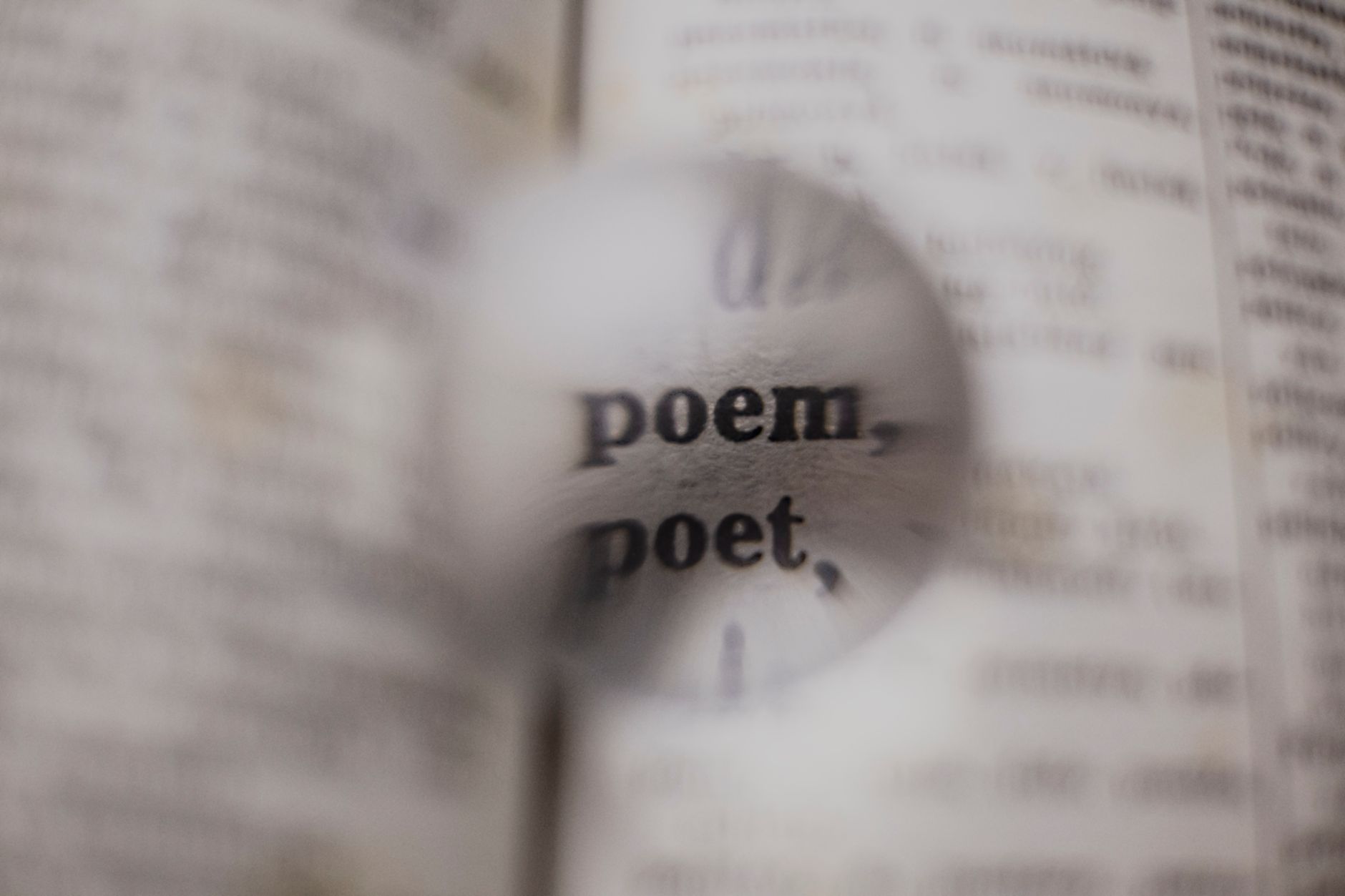 Close-up of words 'poem' and 'poet' magnified in a dictionary