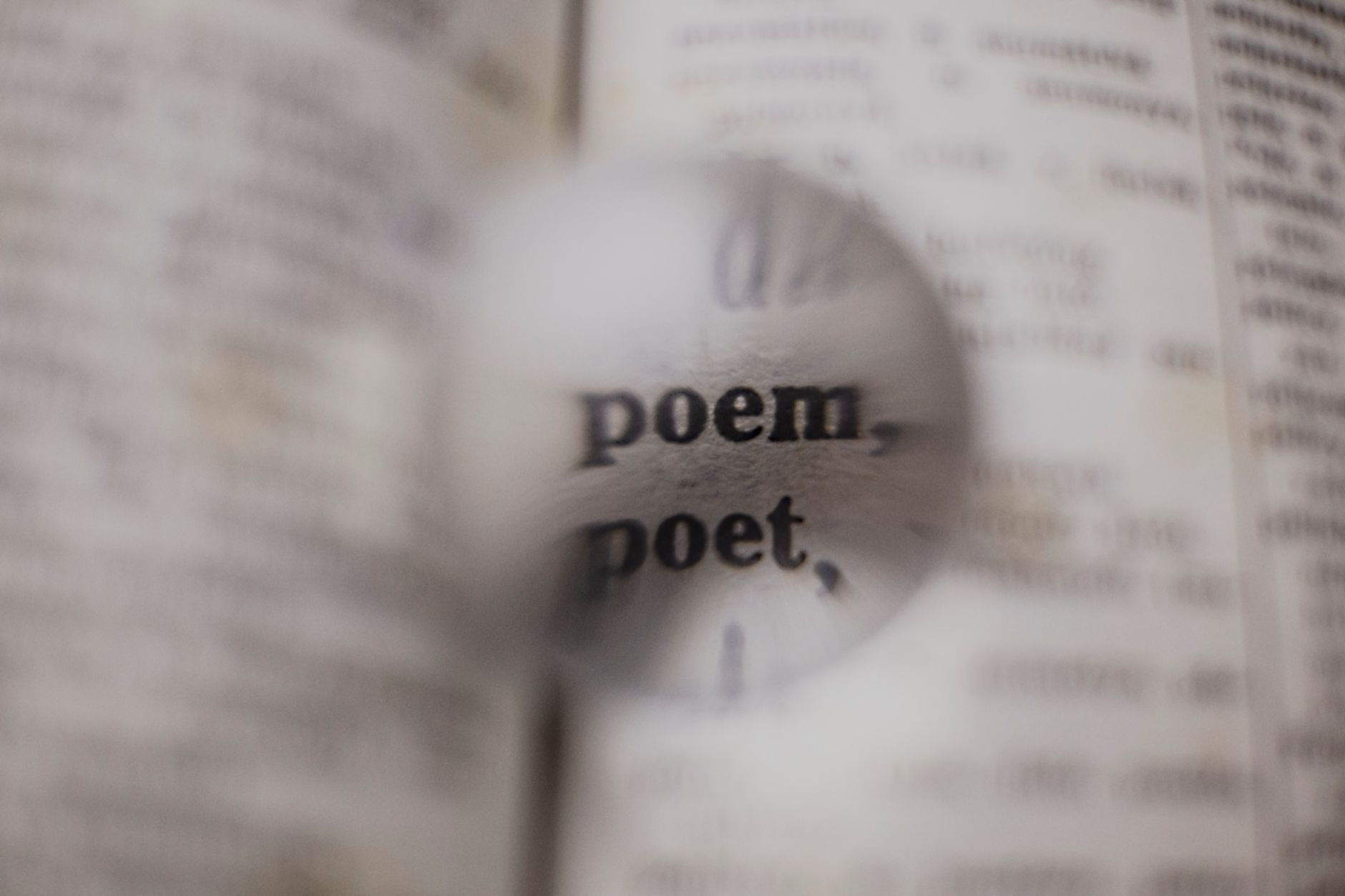 Close-up of words 'poem' and 'poet' magnified in a dictionary