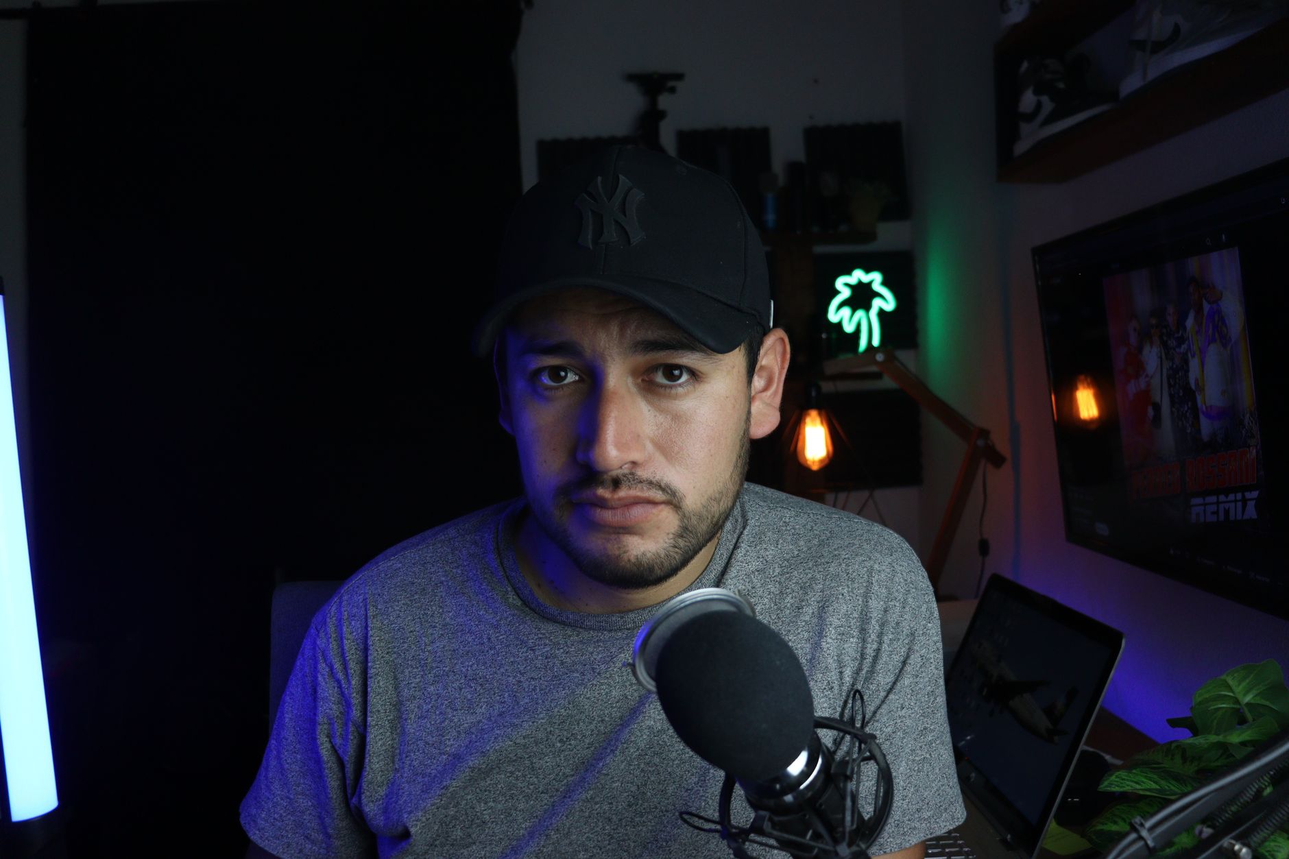 Male content creator in a home studio setup with microphone and soft lighting.