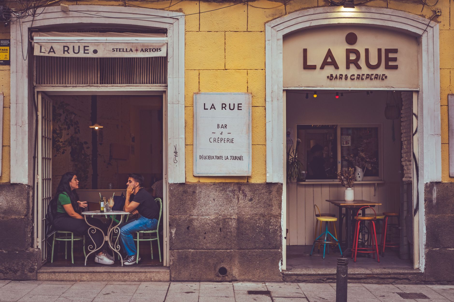 Casual outdoor café setting in Madrid featuring two people enjoying a drink.