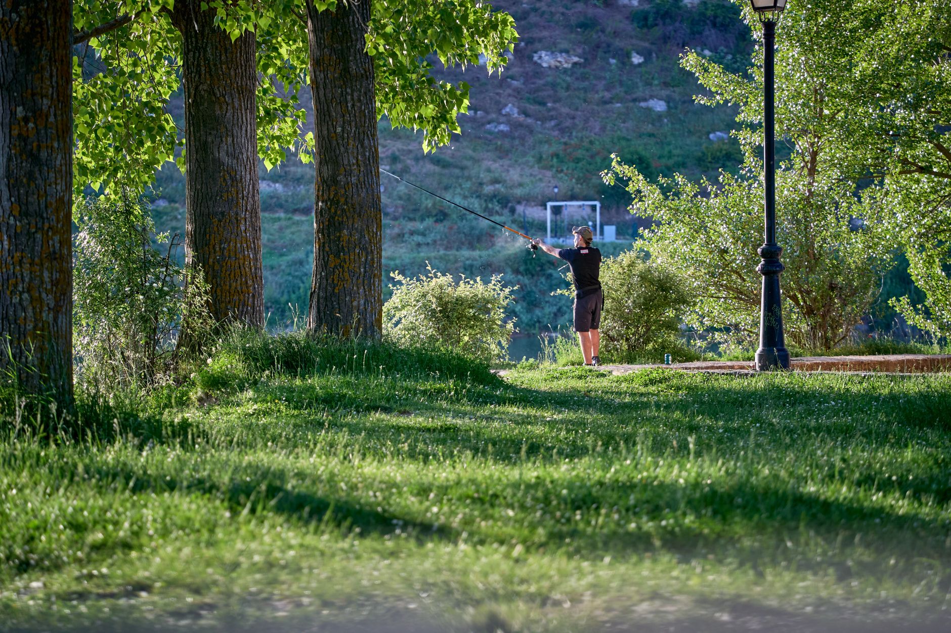 A person fishing in the serene green landscape of Maderuelo, Spain.